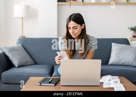 Young adult woman calculating household expenses at home Stock Photo