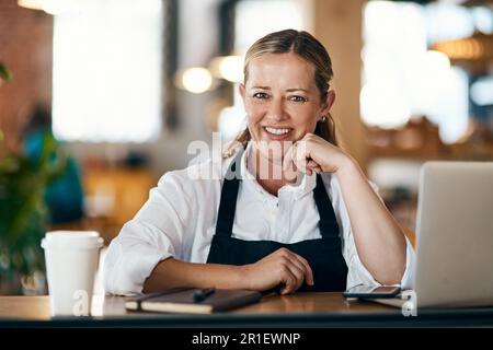 A positive mind is a make it happen mind. a mature woman using a laptop and laptop while working in a cafe. Stock Photo
