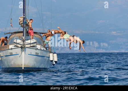 People jumping from a boat to the sea Stock Photo