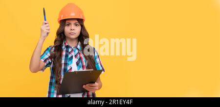 Builder teenager girl in helmet. serious child in construction helmet working with clipboard, under control. Child builder in helmet horizontal poster Stock Photo