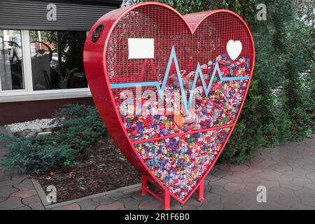 Heart shaped red recycling container for plastic caps outdoors Stock Photo