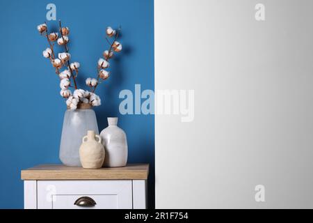 Vases and cotton branches on wooden table indoors. Space for text Stock Photo