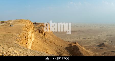 Car on the edge of the Jabal Tuwaiq Mountains, with desert landscape ...