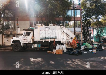 a garbage truck collects rubbish from a street in Mexico City, trash is typically brought to the truck by residents rather than left on the sidewalk Stock Photo