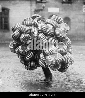 Archival Photo: A basket peddler carrying baskets in the street of an Austrian city ca. 1908-1919 Stock Photo