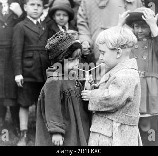 Archival Photo: Two young children at the White House Easter Egg Roll sharing a bottle of juice or soda ca. 1922 Stock Photo