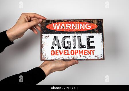 AGILE DEVELOPMENT. Warning sign with text in the hands of a woman. Stock Photo
