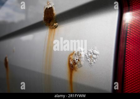 Blown paint bubble and rust spot on the car. Peeled paint. Stock Photo