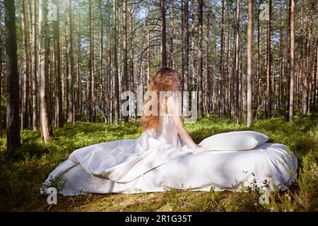 Woman sleeps on a mattress in the summer forest. The girl is resting in nature Stock Photo