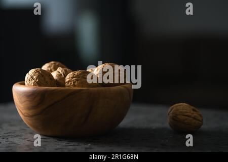inshell walnuts in olive wood bowl on terrazzo countertop, shallow focus Stock Photo
