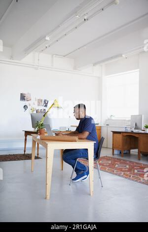 Creative, office or black man typing on laptop working on a blog project, digital or online research. Coworking, planning or focused African designer Stock Photo