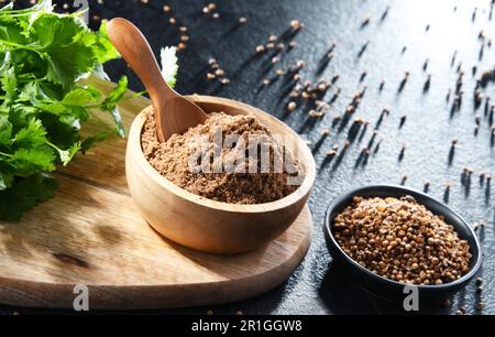 Composition with ground coriander, its dried seeds and fresh leaves Stock Photo