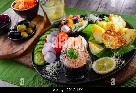 Fried salmon with potatoes and vegetable salads Stock Photo