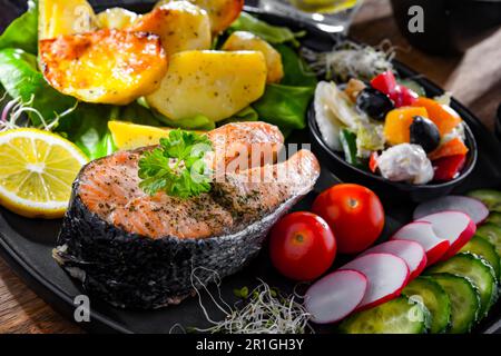 Fried salmon with potatoes and vegetable salads Stock Photo