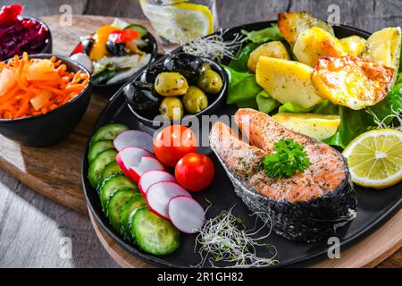 Fried salmon with potatoes and vegetable salads Stock Photo