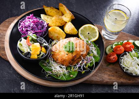 Pulled chicken cutlet coated with breadcrumbs with potatoes and vegetable salads Stock Photo