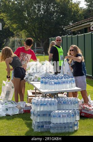 Teenagers with a mountain of bottled water helping at the Framlingham Flyers 10km road race by packing the goodie bags at the finish Stock Photo