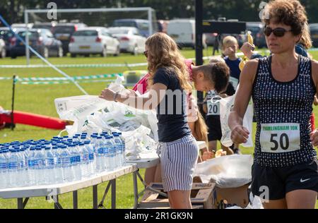 Teenagers with a mountain of bottled water helping at the Framlingham Flyers 10km road race by packing the goodie bags at the finish Stock Photo