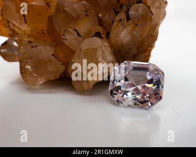 Sparkling asscher cut diamond with rough citrine stone background on a white table Stock Photo