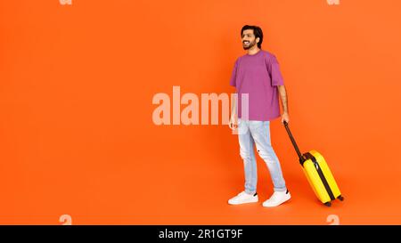 Happy young eastern man with luggage looking at empty space Stock Photo