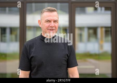 Middle aged man with gray hair looks angry at the camera in front of a glass office building Stock Photo