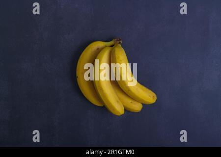 Bunch of bananas on blue dark background. Top view . Copy space Stock Photo