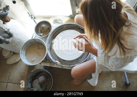 the girl works behind a potter's wheel. View from above. Stock Photo