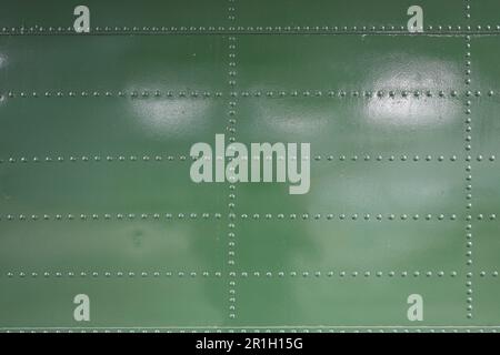 close up of Metal surface of the aircraft fuselage with rivets, Rivets on green metal. Stock Photo