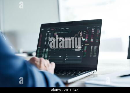Investor analyst analyzing crypto stock market on computer screen. Over shoulder Stock Photo