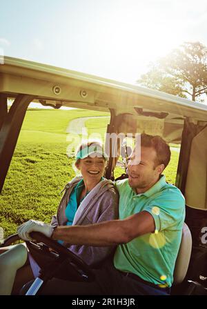Drive it home with love. a couple riding in a golf cart on a golf course. Stock Photo