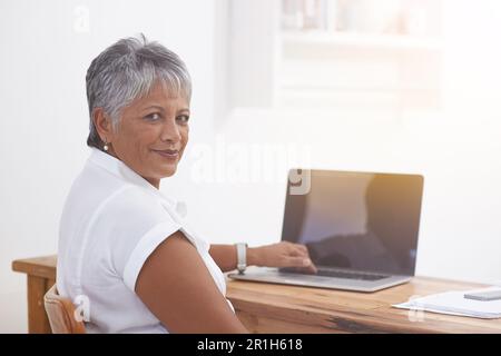 Computer, portrait and senior woman in office smile for online management, digital project and planning or typing. Face of business person Stock Photo