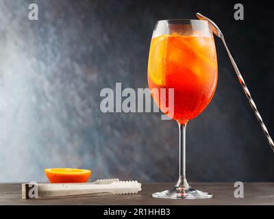 Aperol spritz cocktail and steel bar tools on dark background. Cocktail Aperol Spritz and an orange slice. Copy space Stock Photo