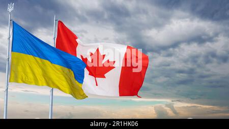 Ukraine and Canada two flags on flagpoles and blue sky. Stock Photo