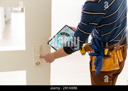 Side view of male technician examining fusebox while holding tablet Stock Photo