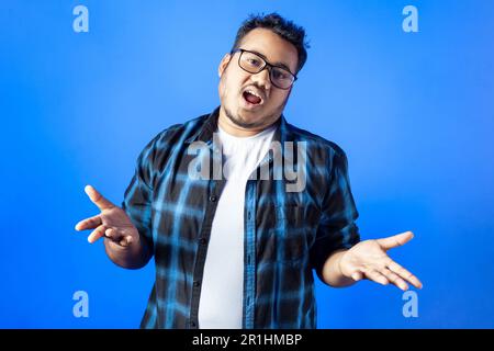 One Indian young guy showing I have no idea gesture over blue background Stock Photo