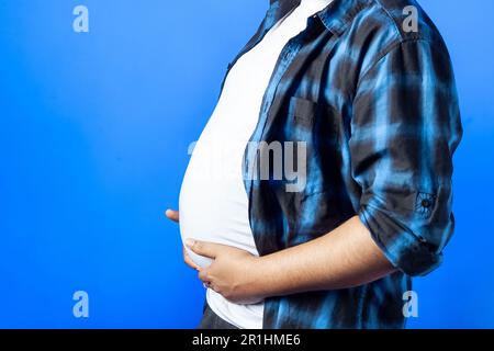 obesity, healthy food and weight loss concept. Side view of an Indian man touching and showing belly fat Stock Photo