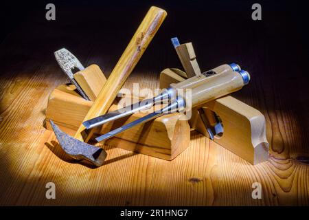 hammer planes chisels for carpenter's manual work, on wooden table and dark background taken with light painting technique Stock Photo