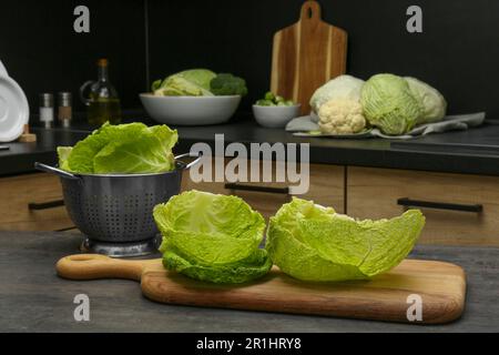 Fresh Savoy cabbage leaves on black table in kitchen Stock Photo