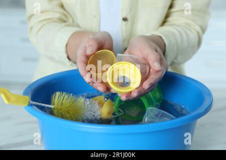 Woman washing baby bottle nipples under stream of water, above