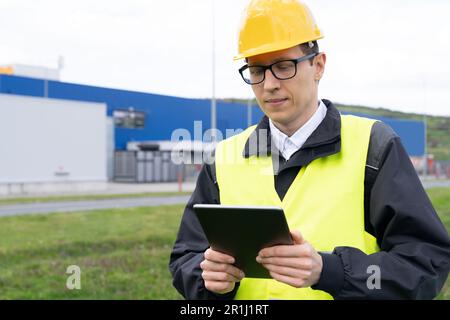 Engineer with digital tablet on a background of modern smart factory. Digital transformation and industry 4.0. High quality photo Stock Photo