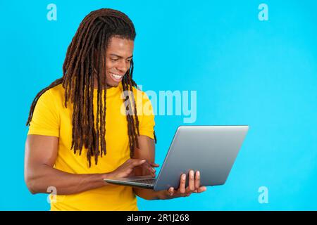 Latin man with dreadlocks smiling while using a laptop Stock Photo