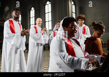 Church choir playing piano and singing together with little girl during performance in church Stock Photo