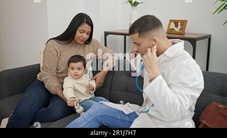 Couple and son examining baby with stethoscope at clinic Stock Photo