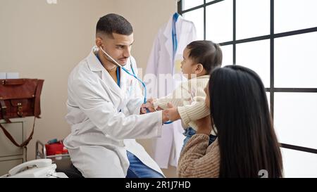 Couple and son examining baby with stethoscope at clinic Stock Photo