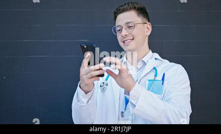 Young hispanic man doctor smiling confident using smartphone over isolated black background Stock Photo