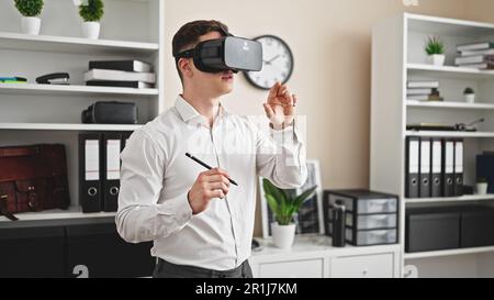 Young hispanic man architect wearing virtual reality glasses drawing at office Stock Photo