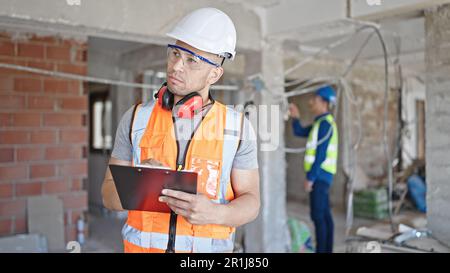 Two men builders writing document working at construction site Stock Photo