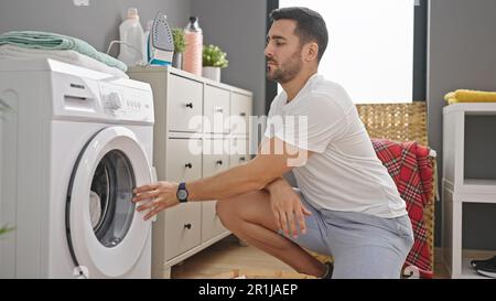 Young hispanic man doing laundry at laundry room Stock Photo