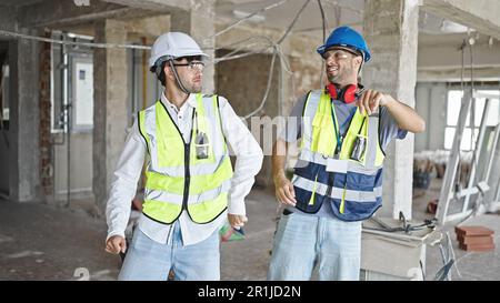 Two men builders smiling confident dancing at construction site Stock Photo