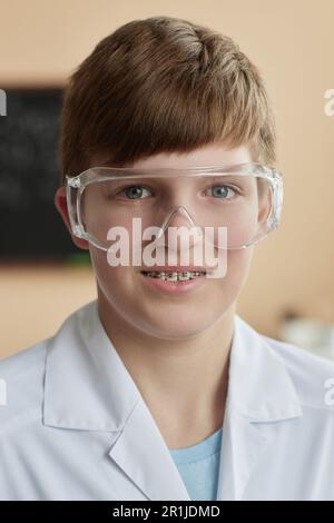 Vertical portrait of smiling teen schoolboy wearing braces in science class and looking at camera Stock Photo